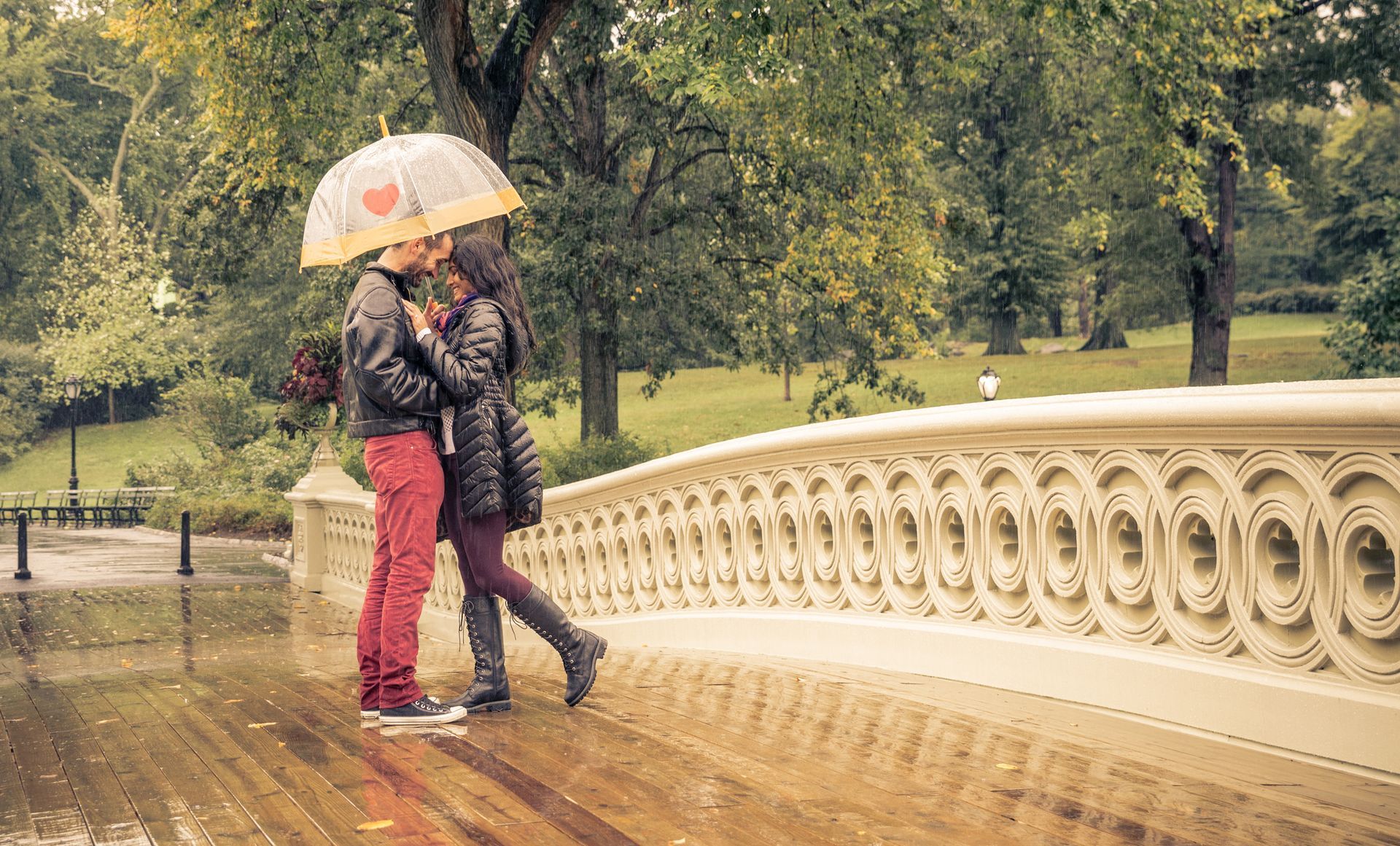 A man and a woman are kissing under an umbrella in the rain.