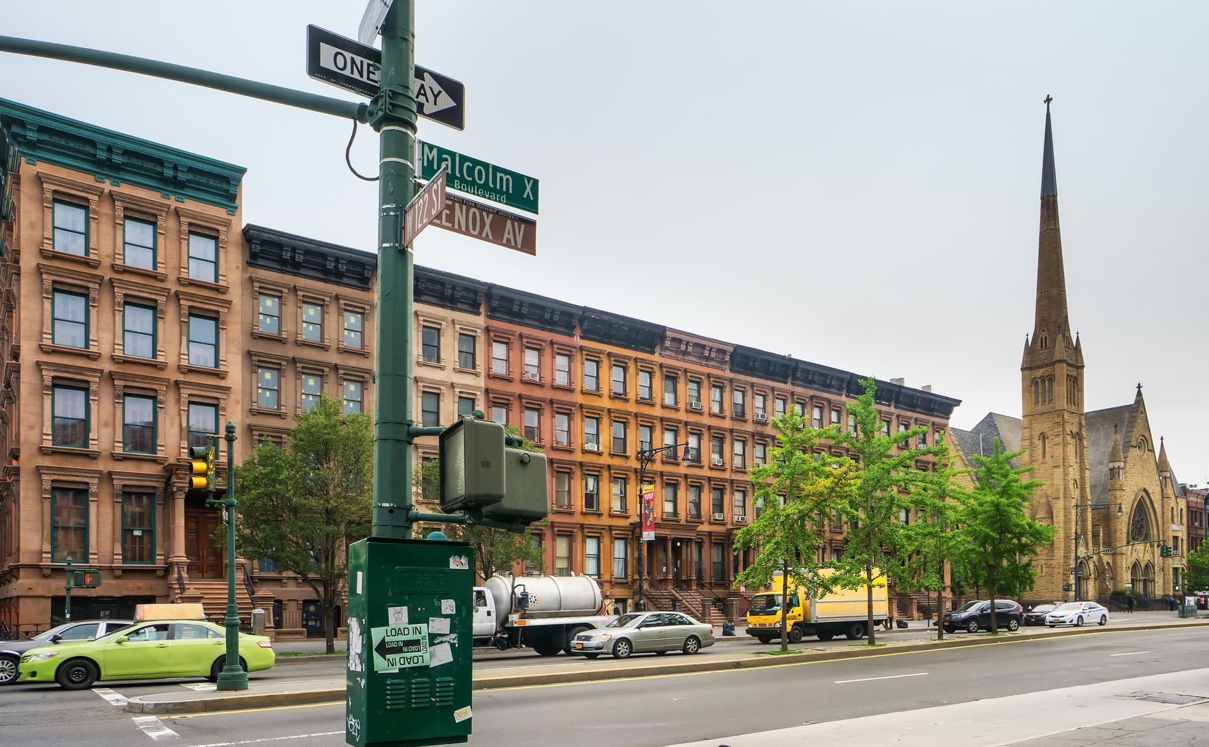 A street in Harlem with a sign that says one way and a church in the background.