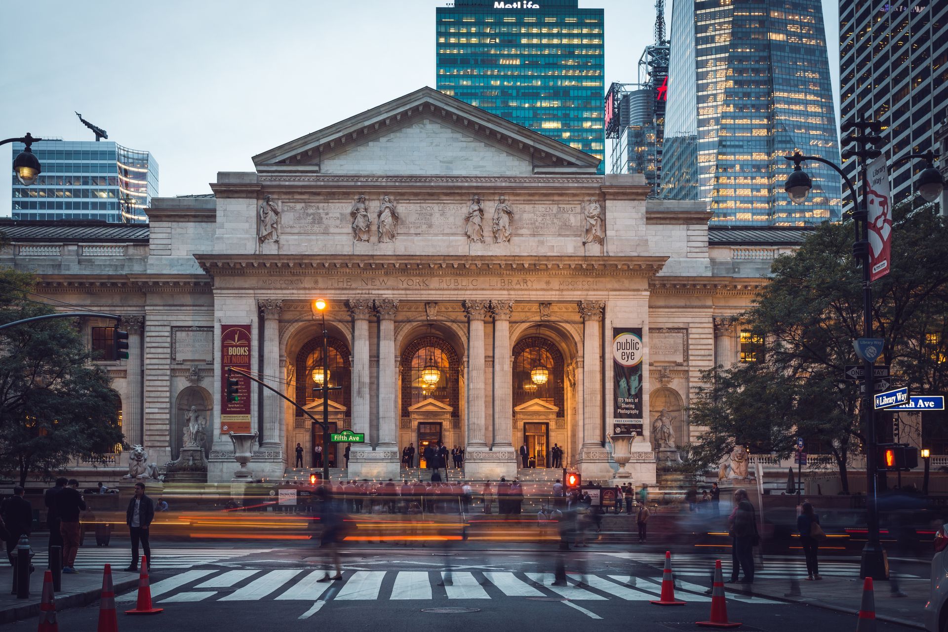 A large building in the middle of a city with people walking in front of it.