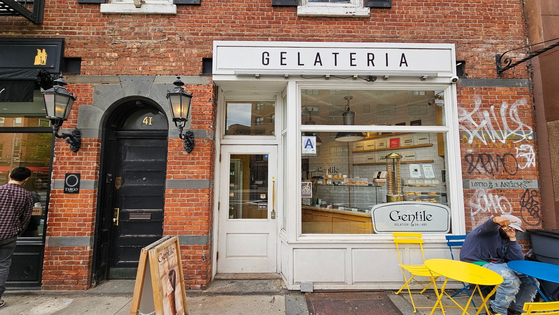 A man is sitting at a table outside of a gelateria