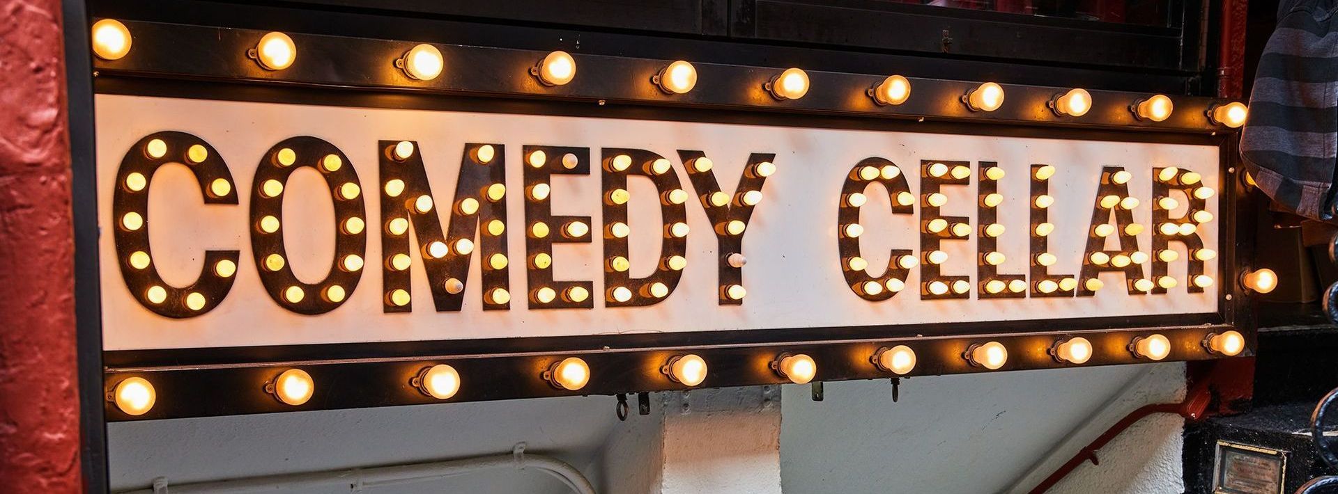 a sign that says comedy cellar with lights on it