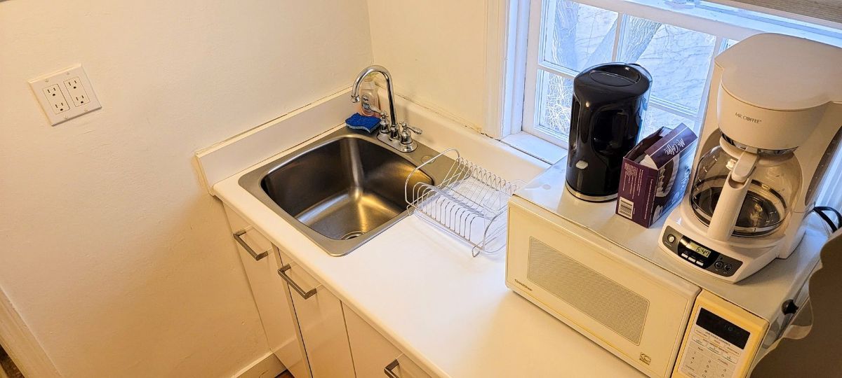a kitchen with a sink , microwave and coffee maker .