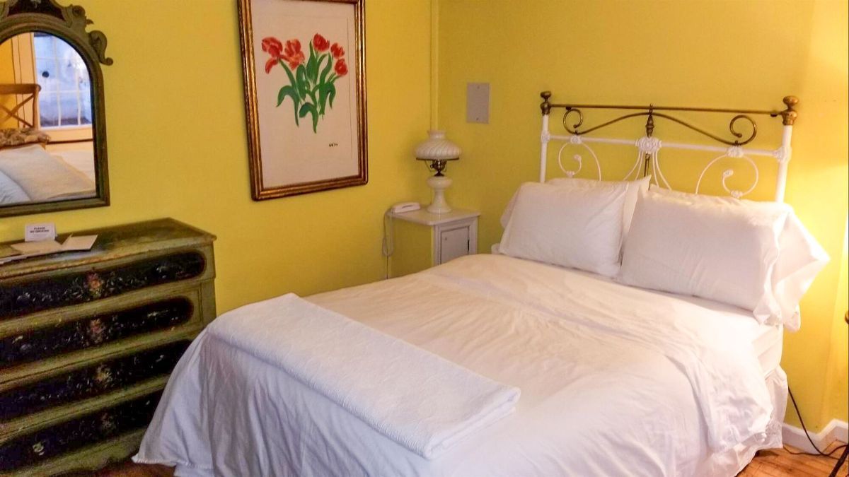 a bedroom with yellow walls and a bed with white sheets