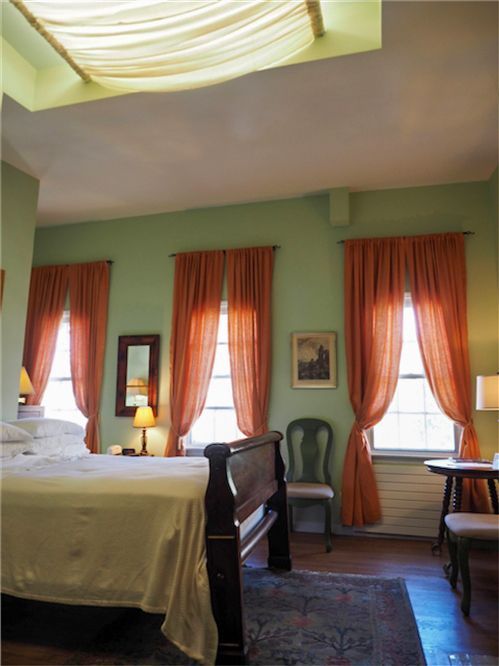 a bedroom with green walls and orange curtains