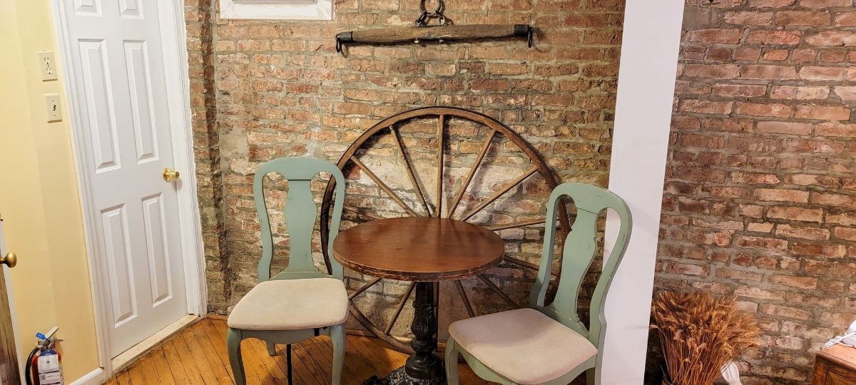 a room with a table and chairs and a wagon wheel on the wall .