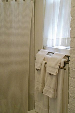 a bathroom with white towels hanging on a towel rack next to a window .