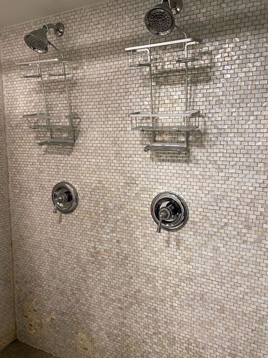 a shower with two shower heads and shelves 