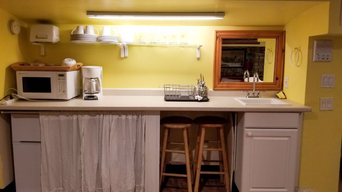 a kitchen with a sink , microwave , coffee maker , and mirror .
