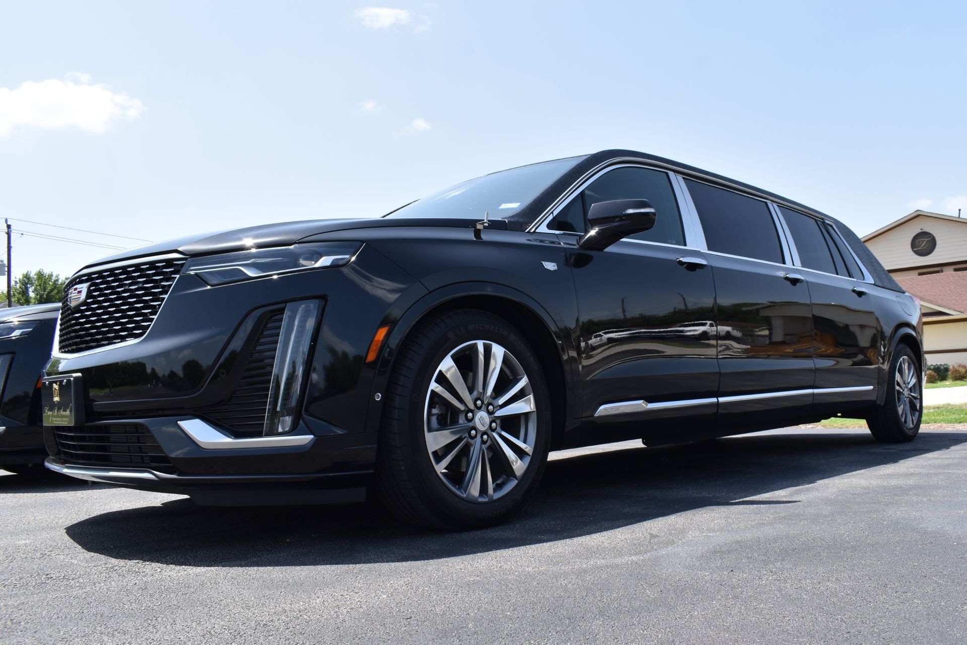 Black Cadillac XT6 limousine parked on asphalt in front of a building.