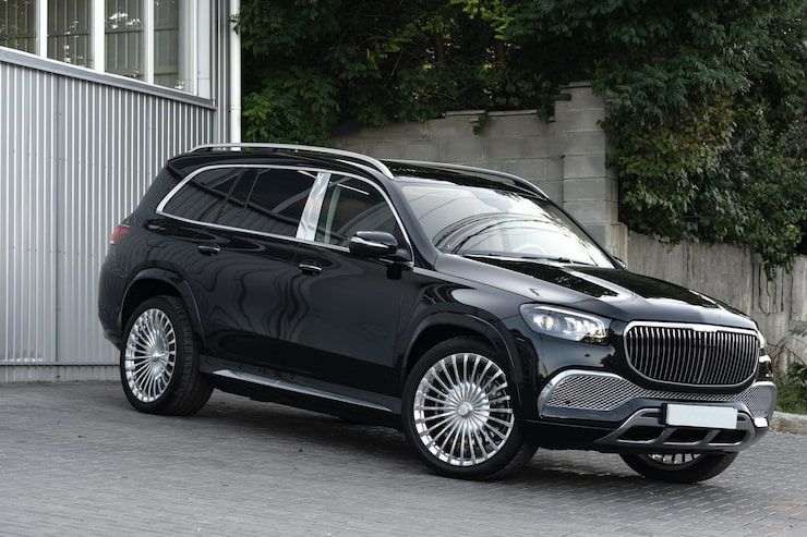 Black limousine parked under an ornate building entrance with palm trees in the background.
