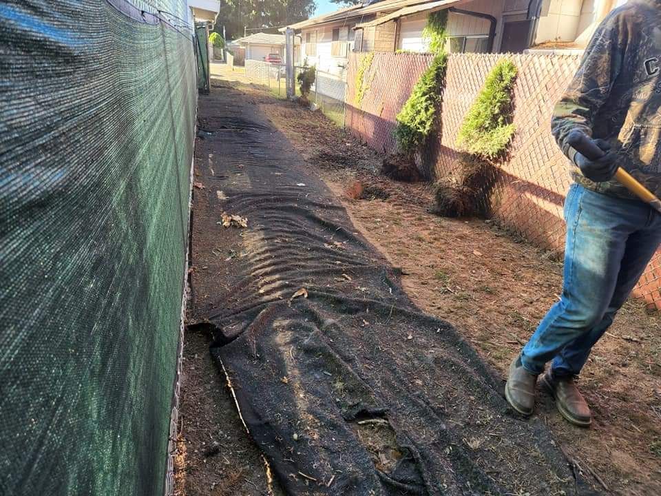 A man is standing next to a fence holding a shovel -  Shelton, WA - D&T Excavating LLP