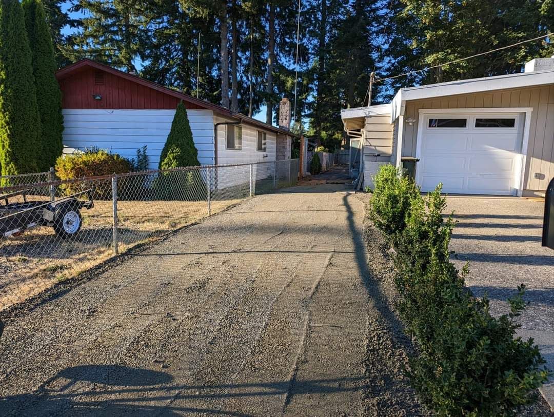 A driveway leading to a house with a garage and a trailer.
