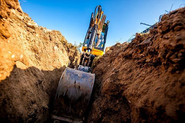 A yellow excavator is digging a hole in the ground.