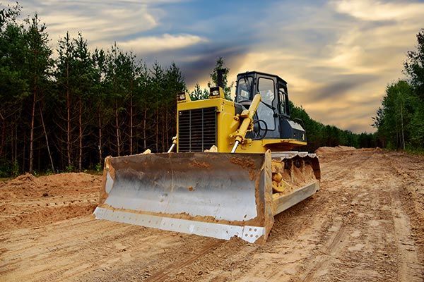 A bulldozer is driving down a dirt road.