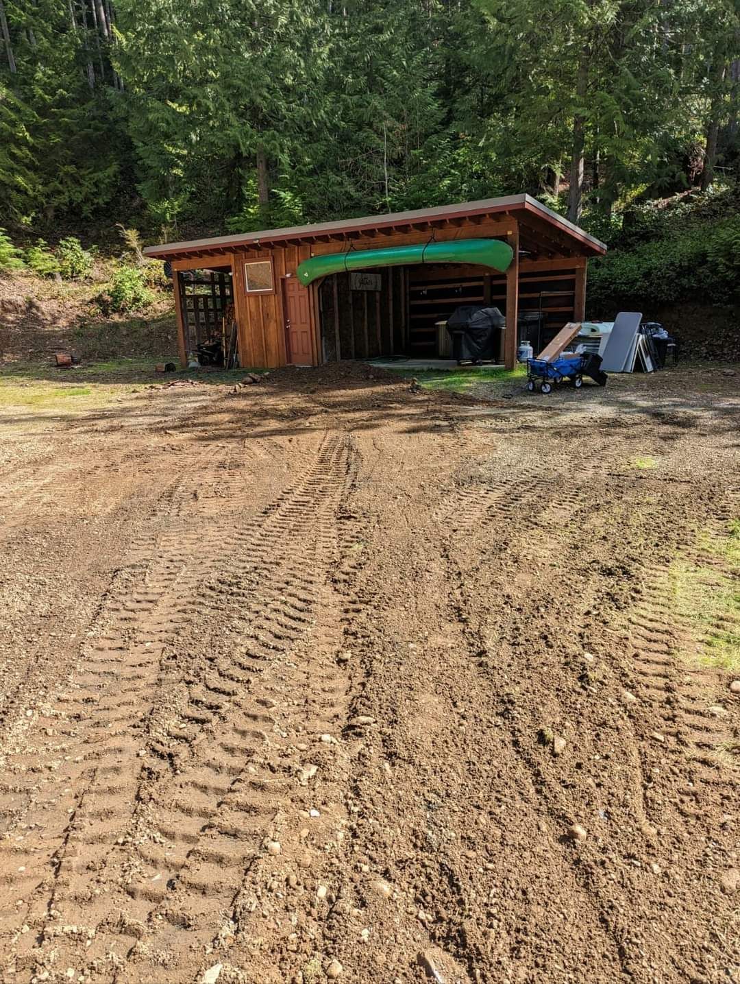 A small wooden shed is sitting in the middle of a dirt field.