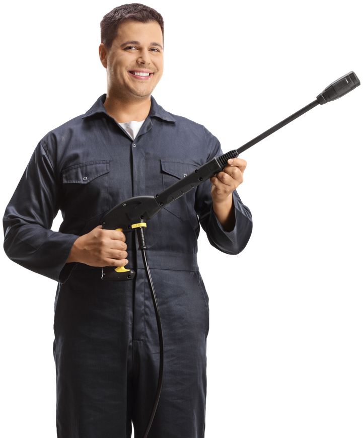 Man in blue jumpsuit holding a pressure washer, smiling.