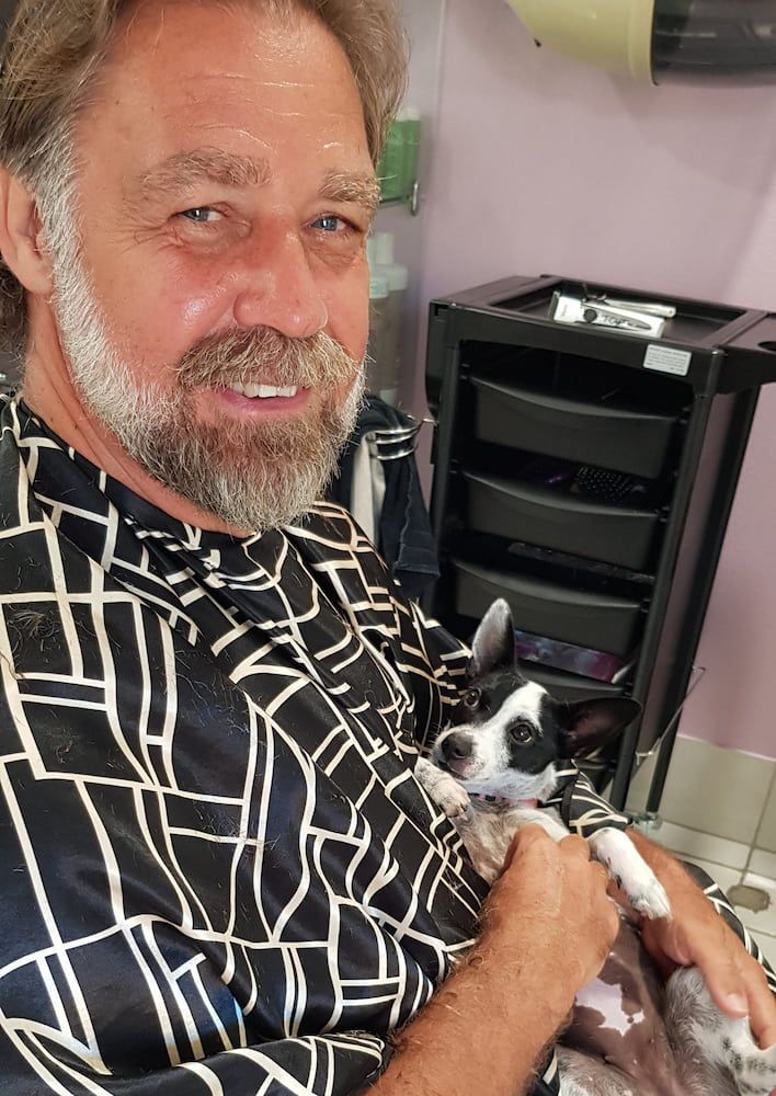 A Man With A Beard Is Holding A Small Dog In His Arms — Spiroll Heated Rollers in Redlynch, QLD