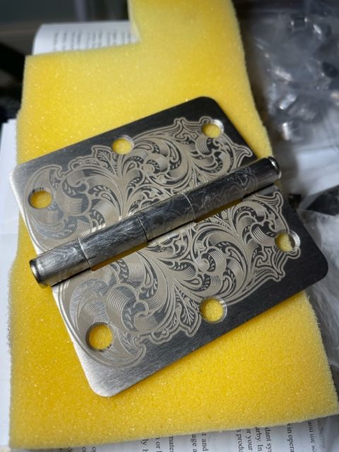 A door hinge with a floral design is sitting on a yellow foam cushion