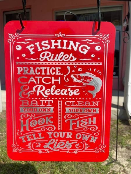 A red sign that says fishing rules practice catch release bait clean your own hook fish tell your own lies