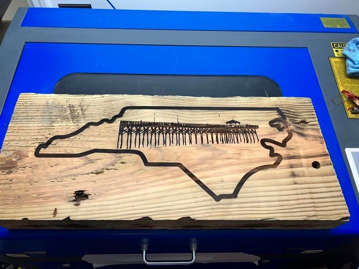 A piece of wood with a map of north carolina on it is sitting on top of a blue table.