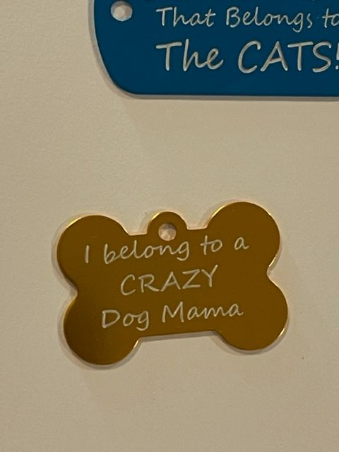 A dog tag that says i belong to a crazy dog mama