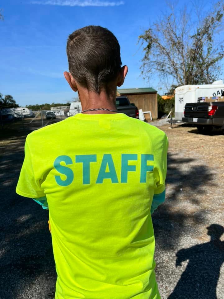 A man wearing a neon yellow staff shirt is standing in a parking lot.