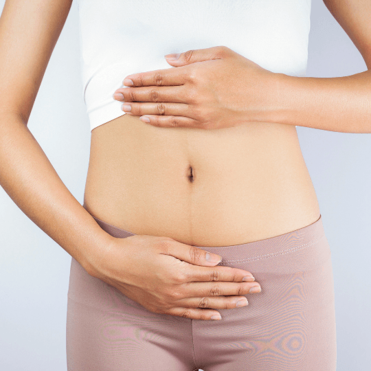 A woman is holding her stomach with her hands.