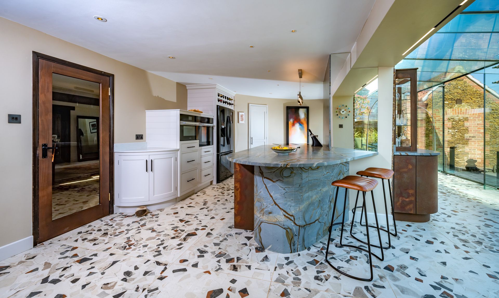 A kitchen with a large island and stools in it.