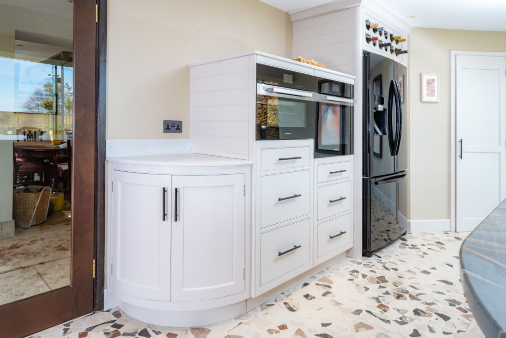 A kitchen with white cabinets , a black refrigerator and a microwave oven.