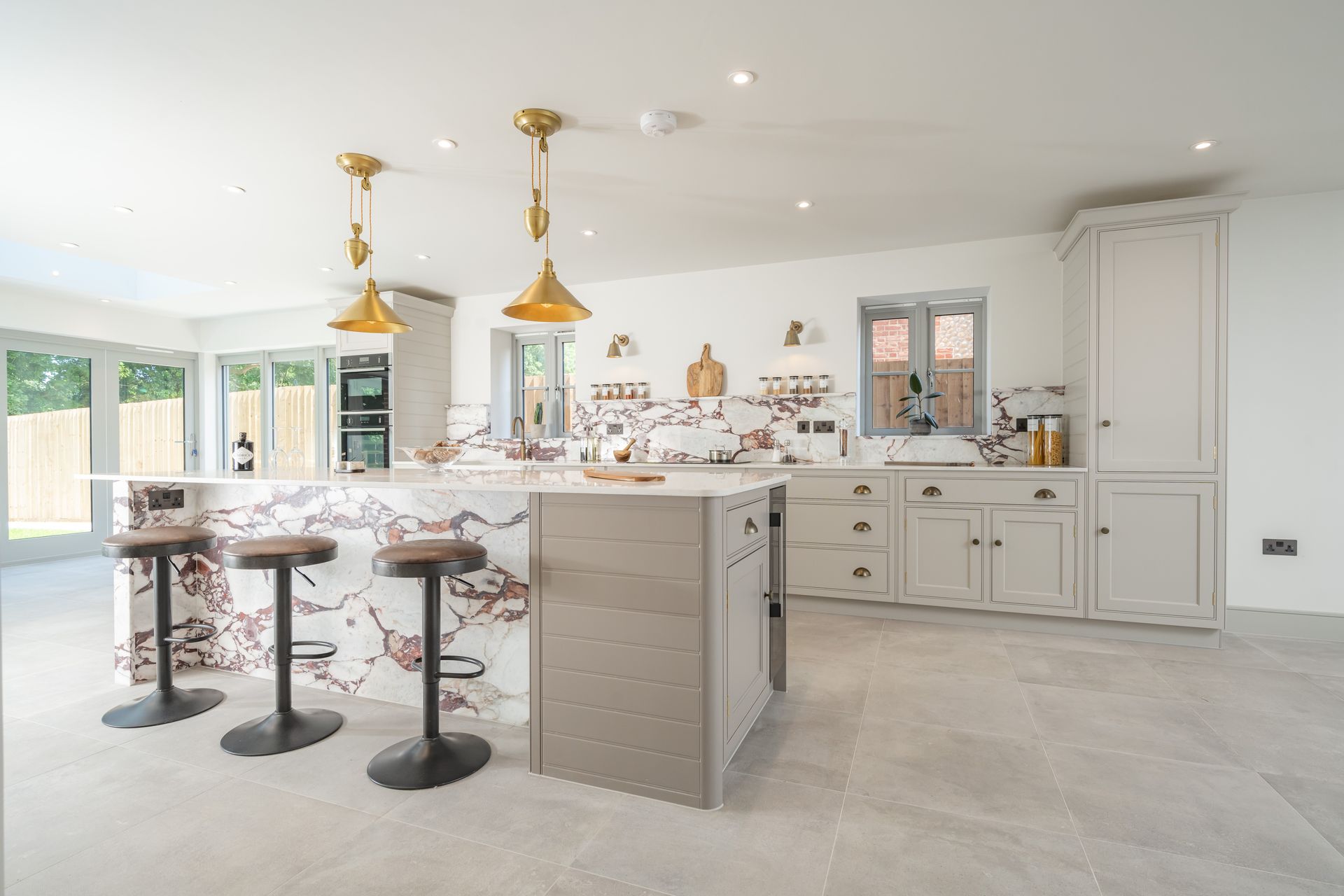 A kitchen with a large island and three stools.