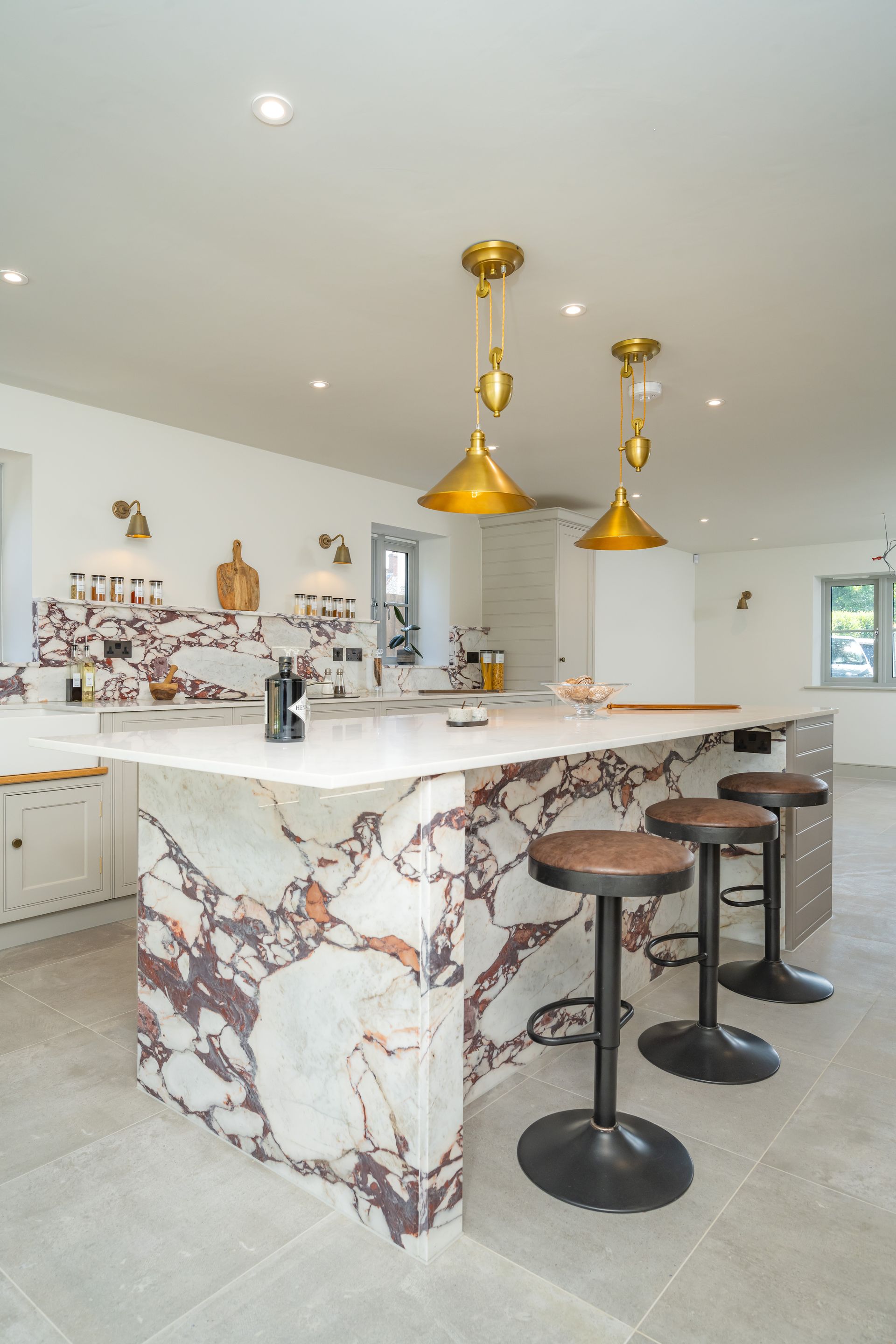 A kitchen with a marble counter top and stools