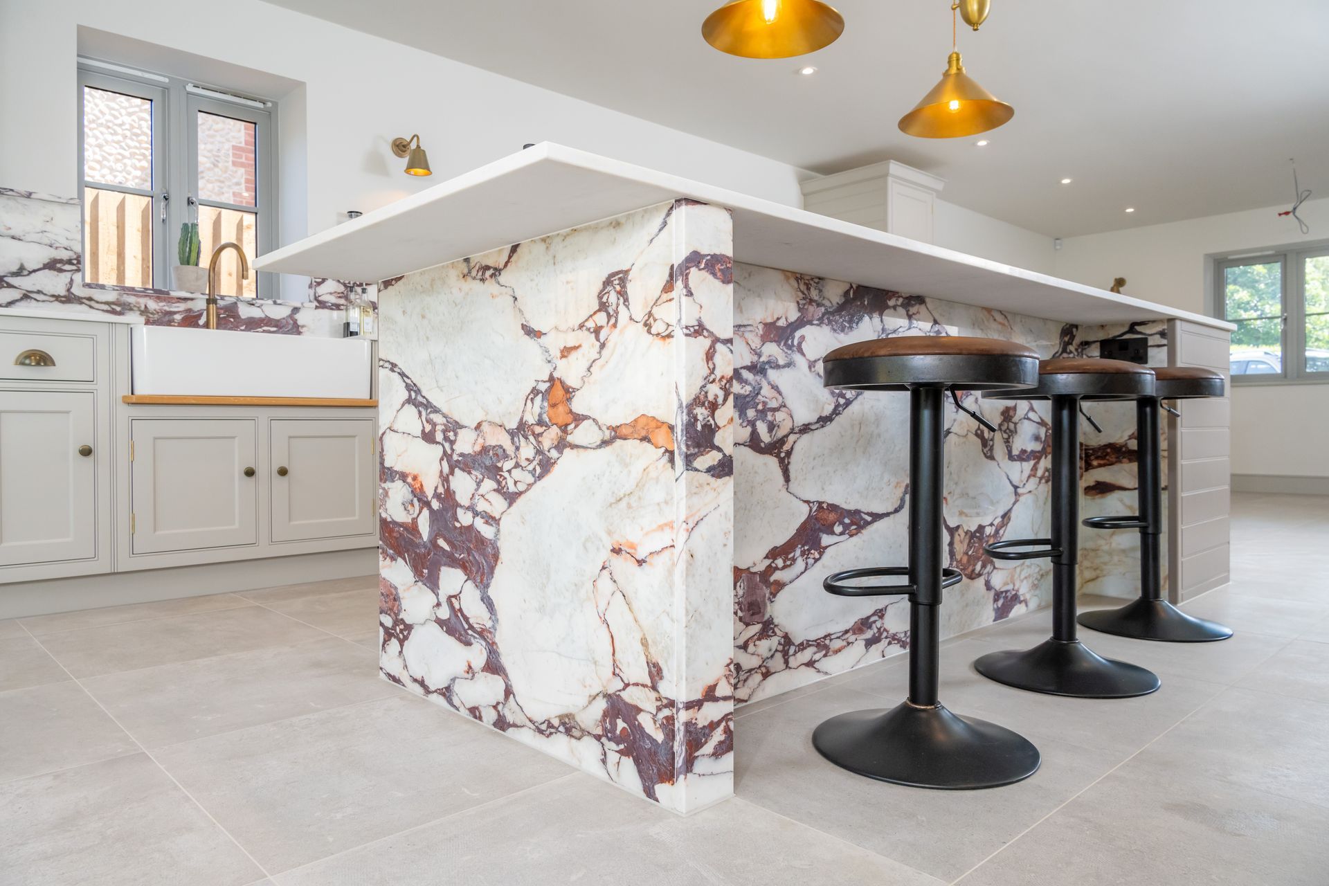 A kitchen with a large island with marble counter tops and stools.