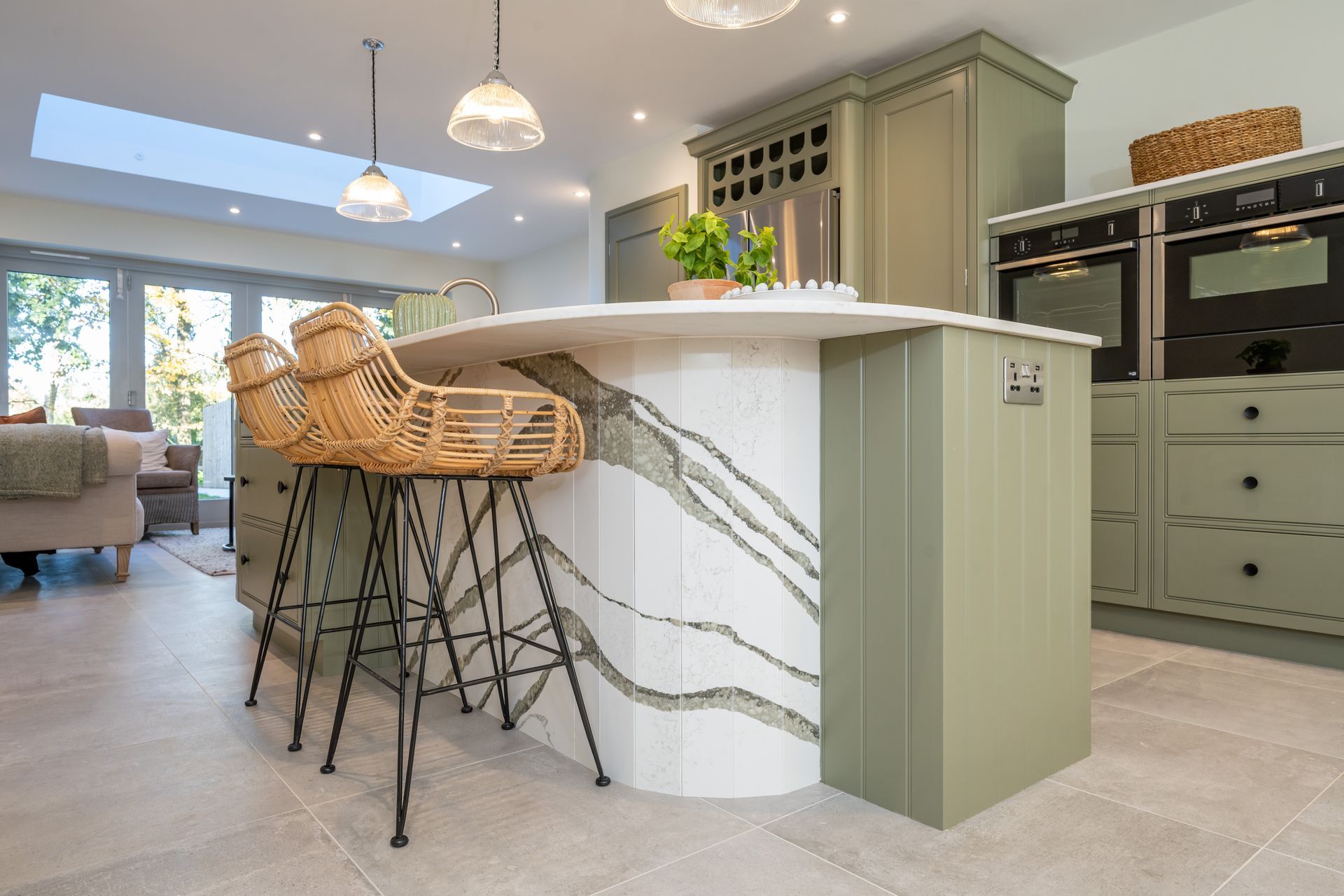 A kitchen with a large island and wicker bar stools.