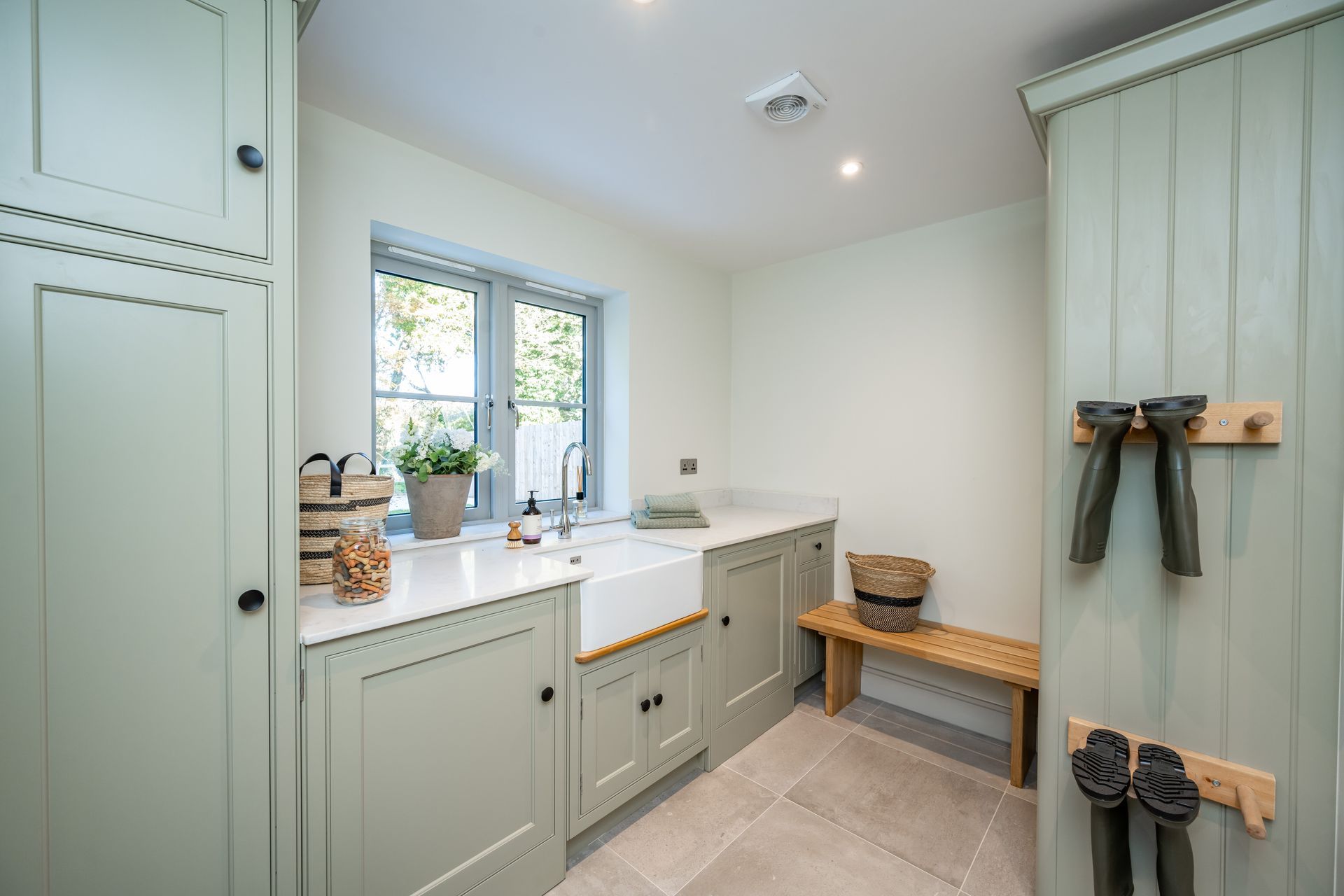A laundry room with a sink , cabinets , and a bench.