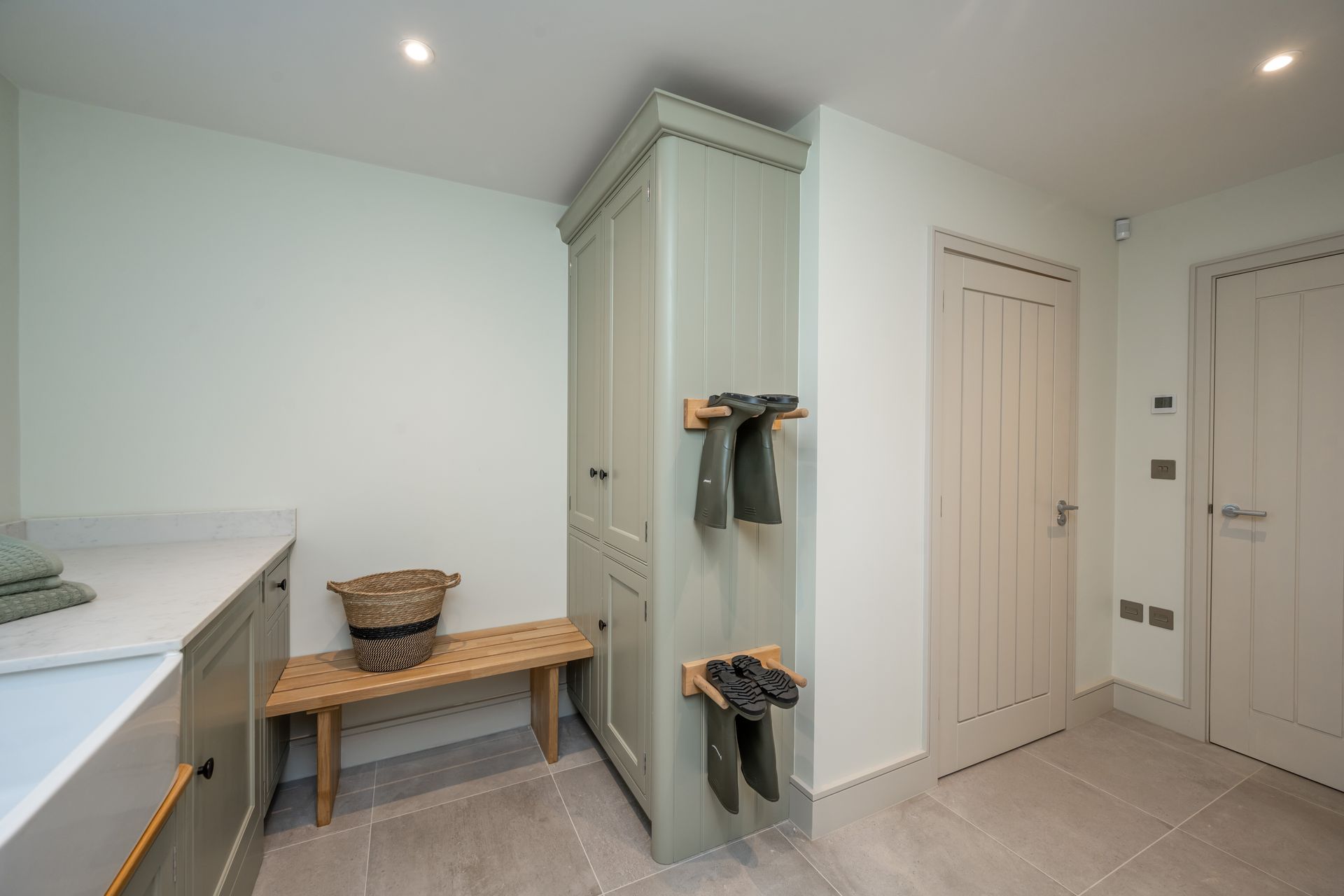 A laundry room with a bench , cabinets , and a door.
