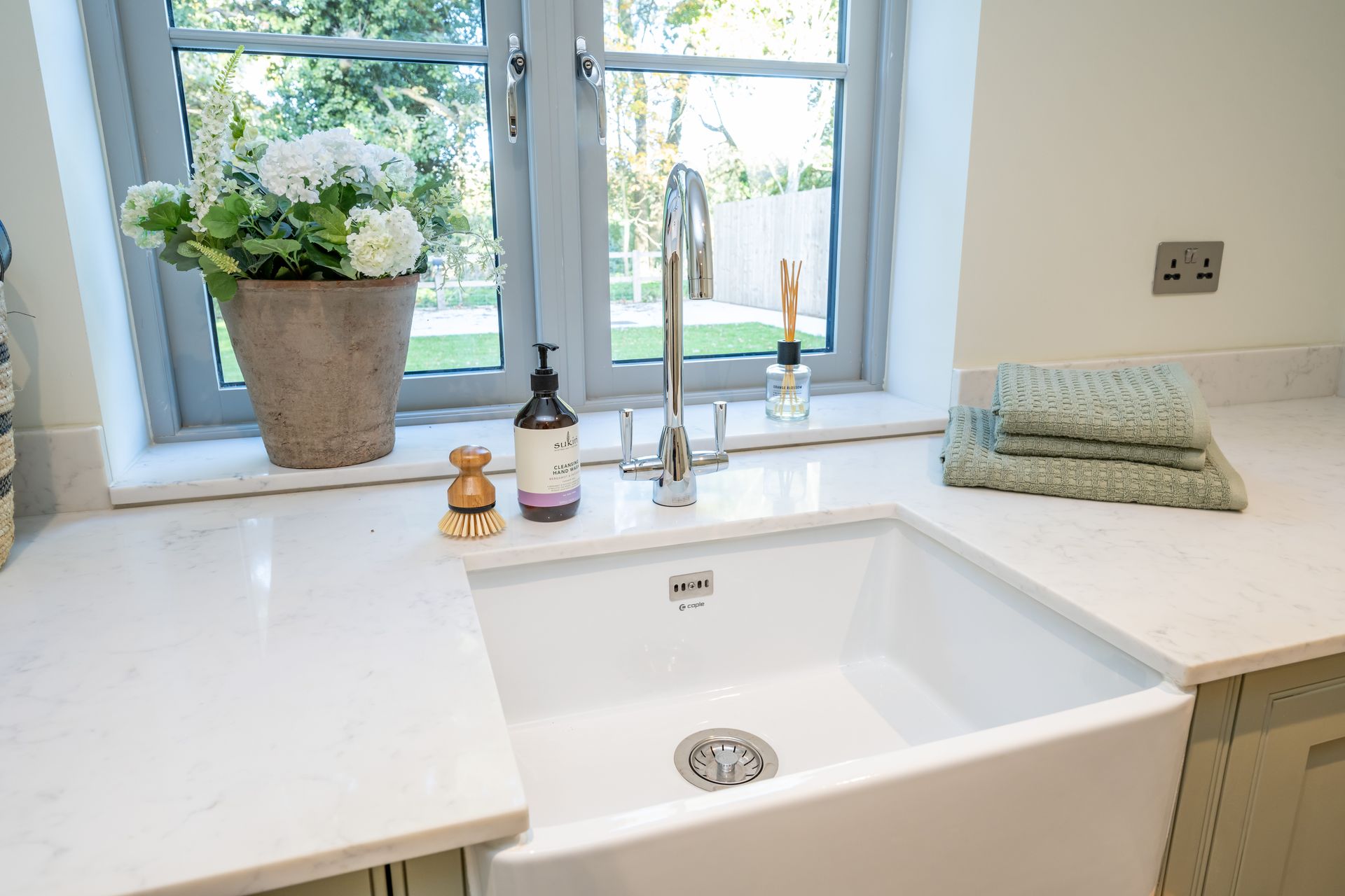 A white kitchen sink is sitting on a counter next to a window.