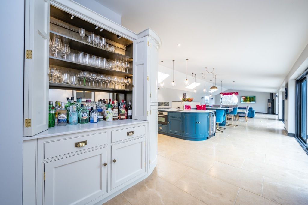 A kitchen with a bar and a lot of bottles and glasses in it.