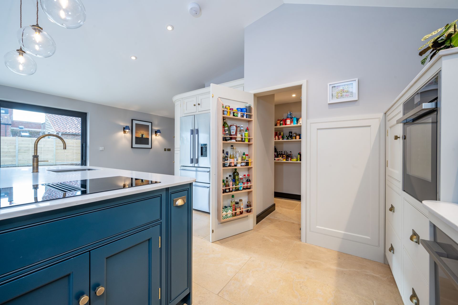 A kitchen with blue cabinets and white counter tops and a pantry.