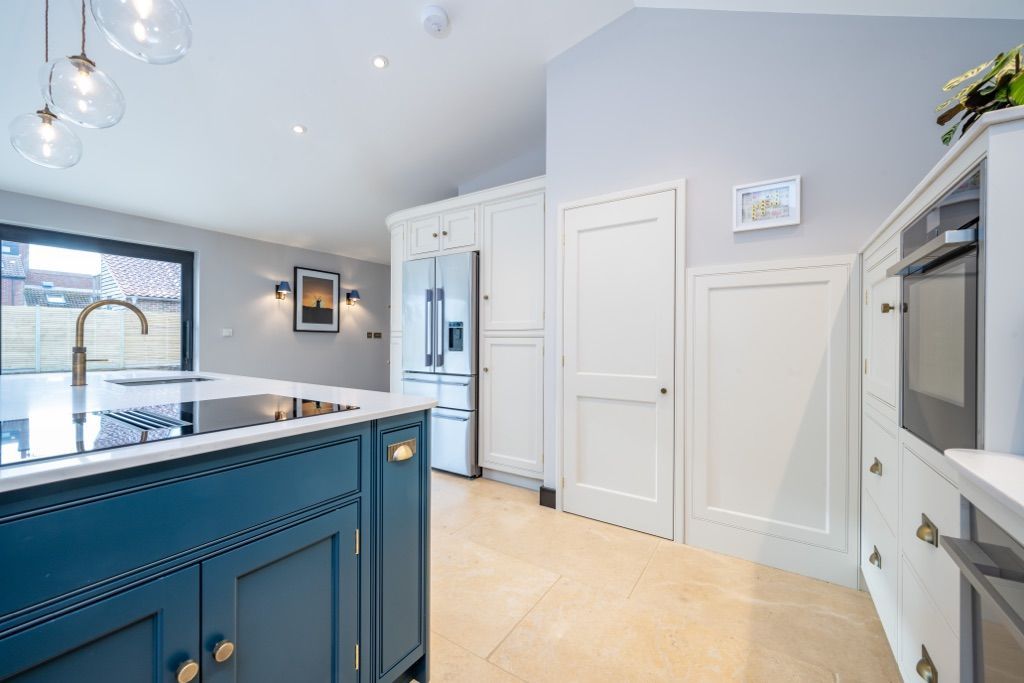 A kitchen with blue cabinets and white appliances and a large island.