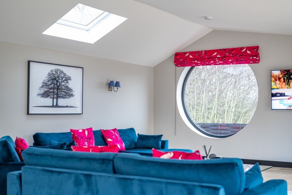 A living room with a blue couch and a round window