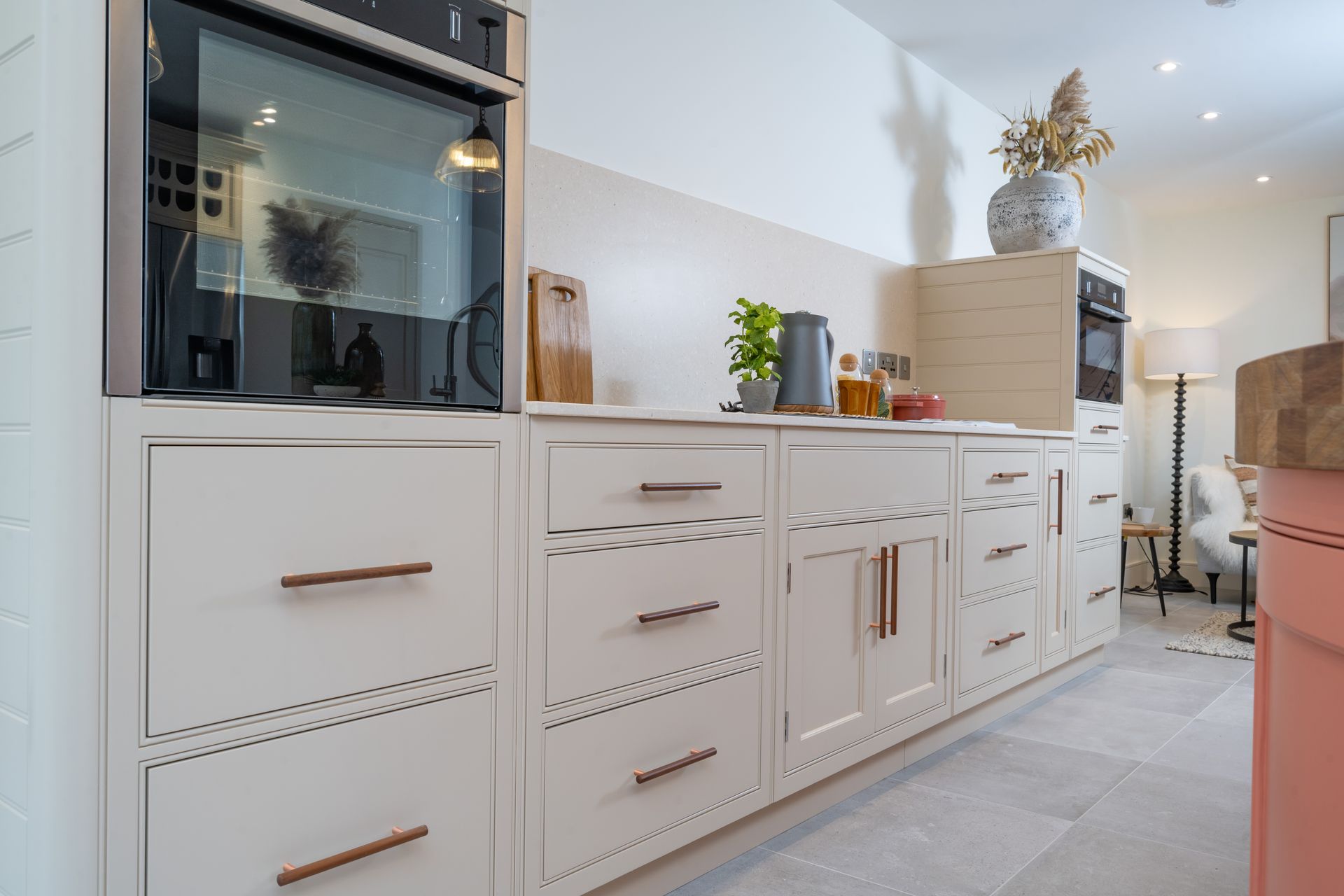 A kitchen with white cabinets and a pink island.