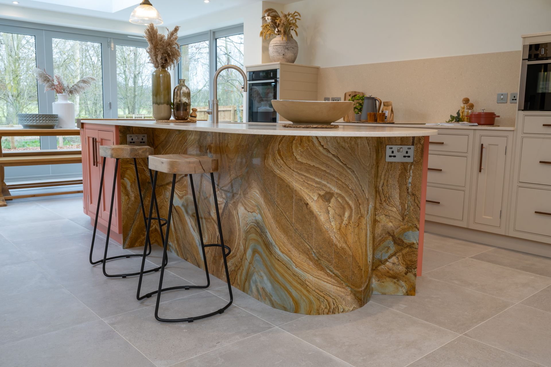 A kitchen with a large island and stools and a sink.