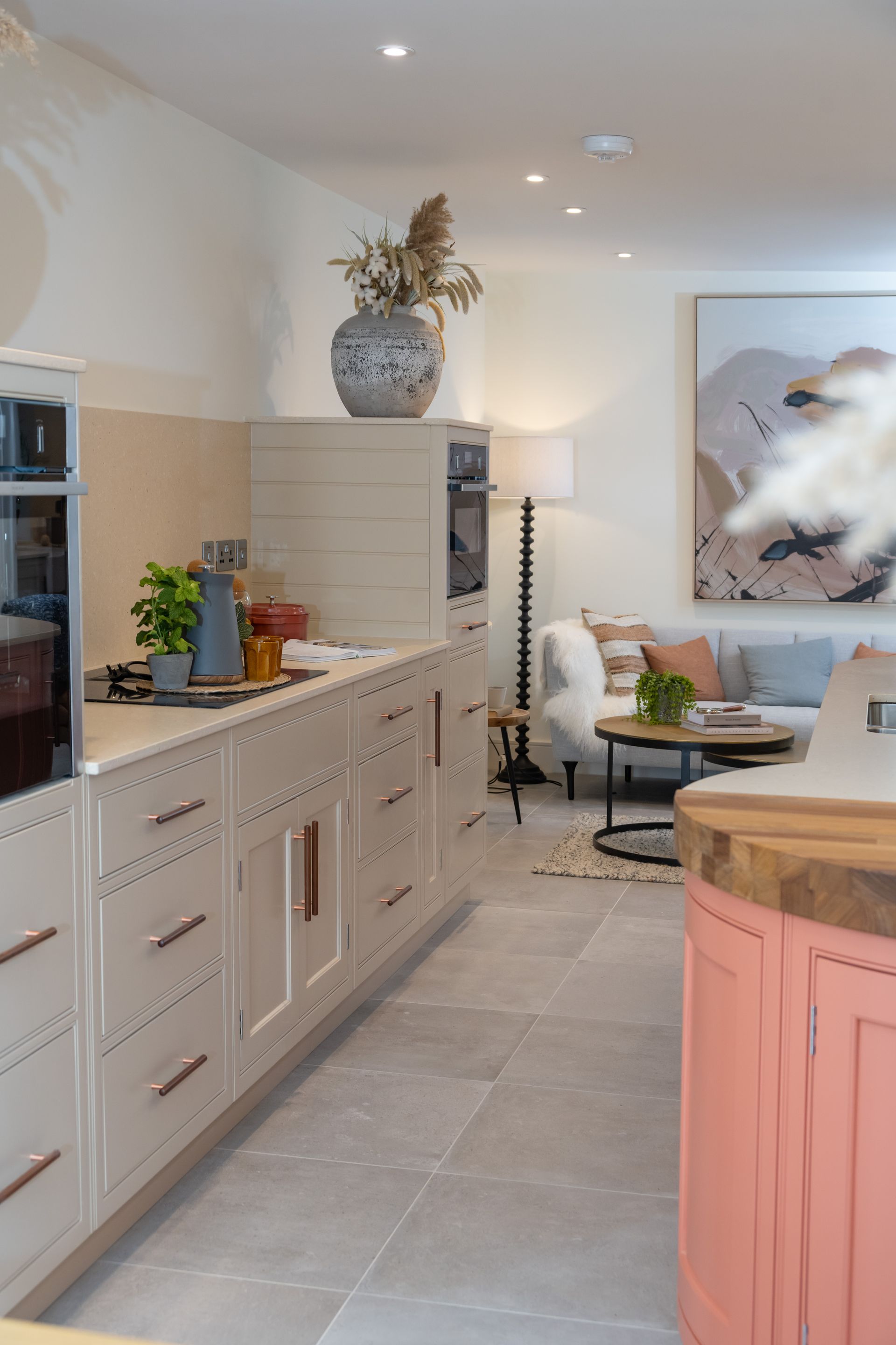 A kitchen with white cabinets and a pink island leading to a living room.