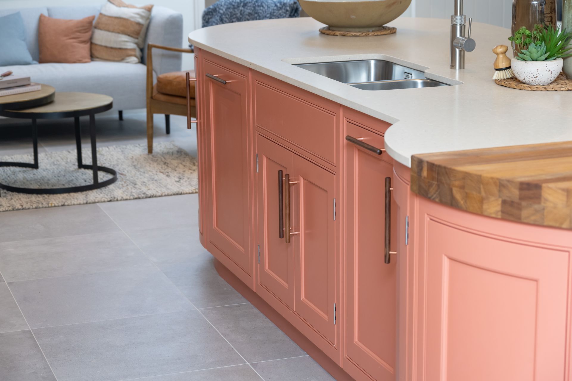 A kitchen with pink cabinets and a wooden counter top.