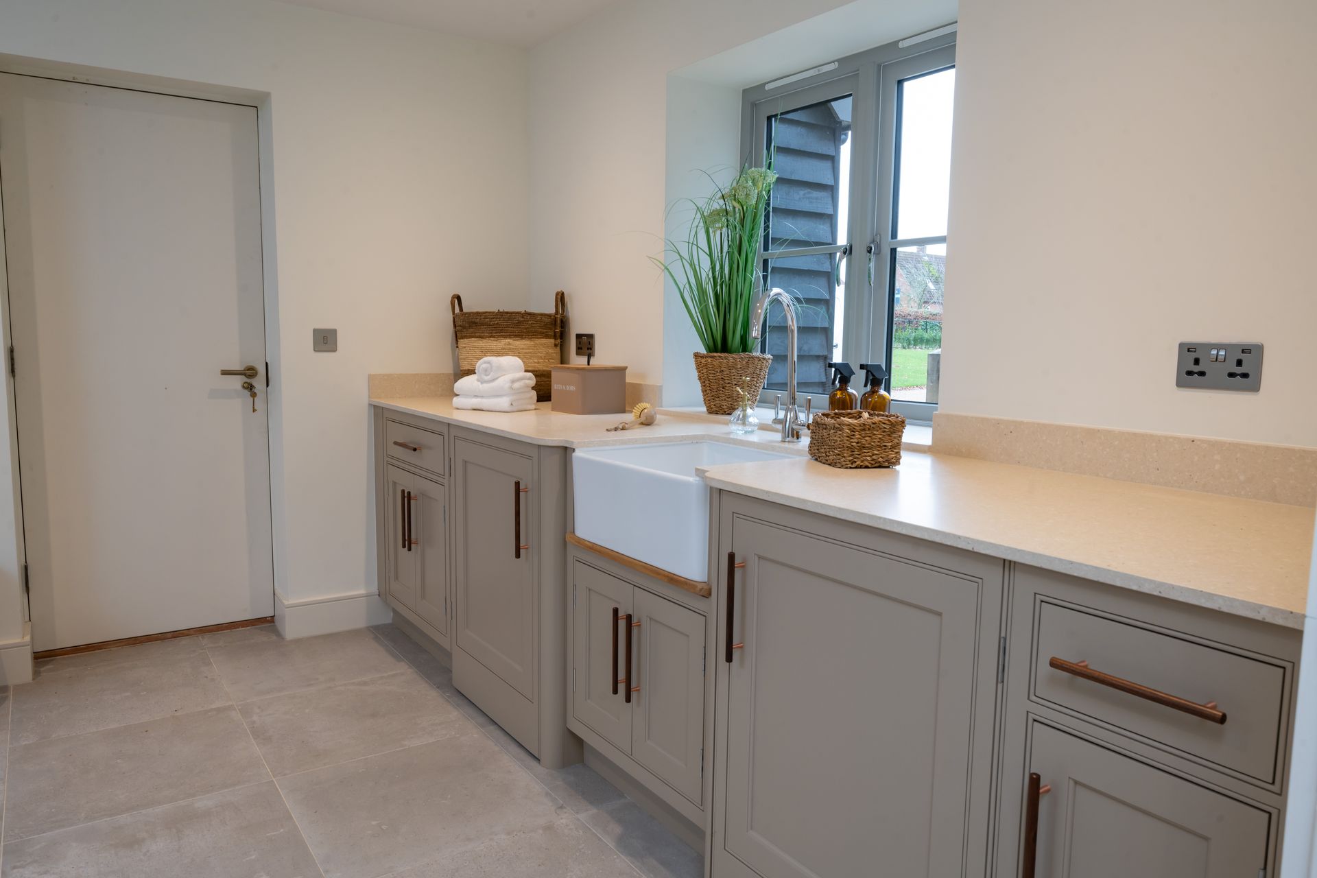 A laundry room with a sink , cabinets and a window.
