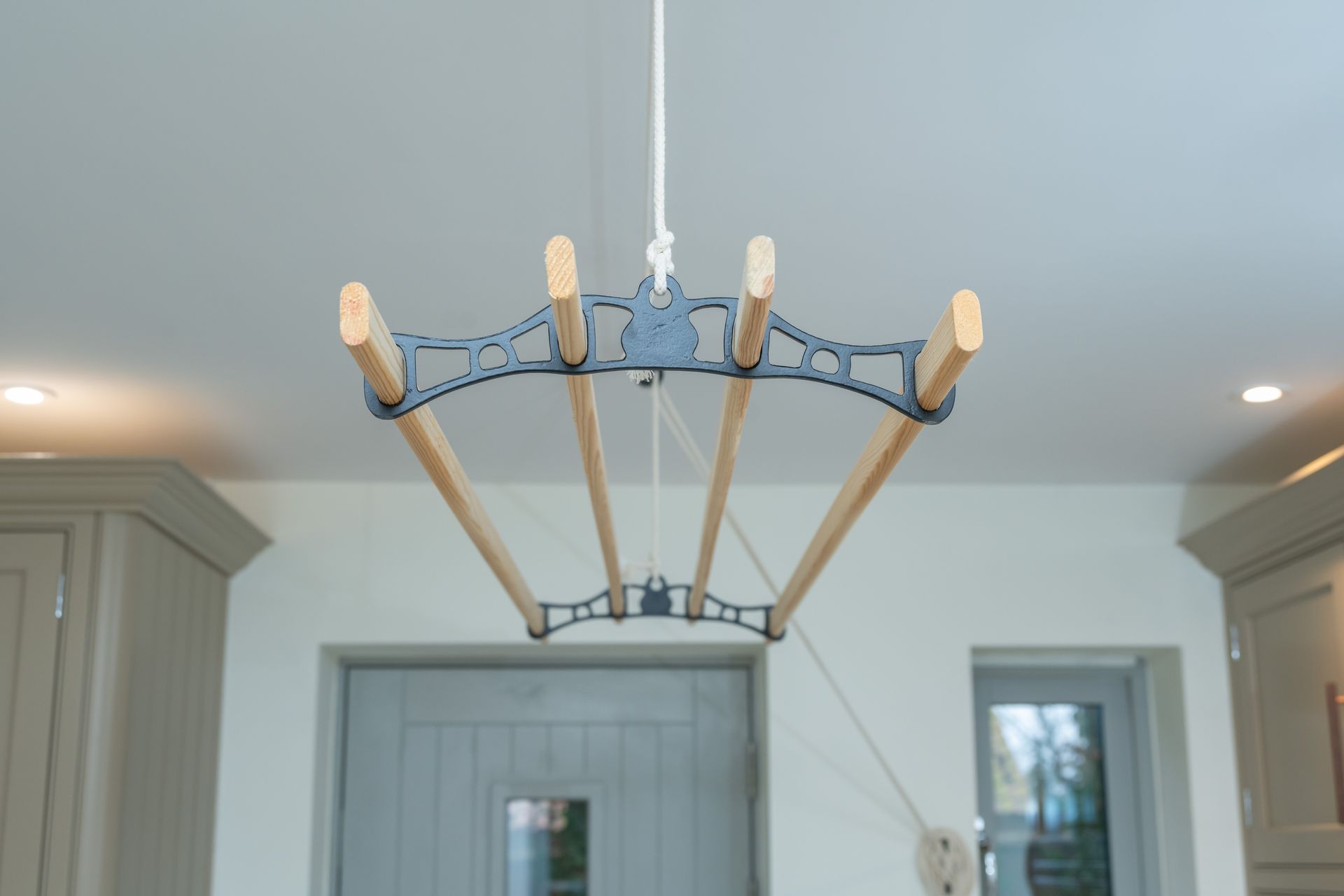 A clothes drying rack is hanging from the ceiling in a kitchen