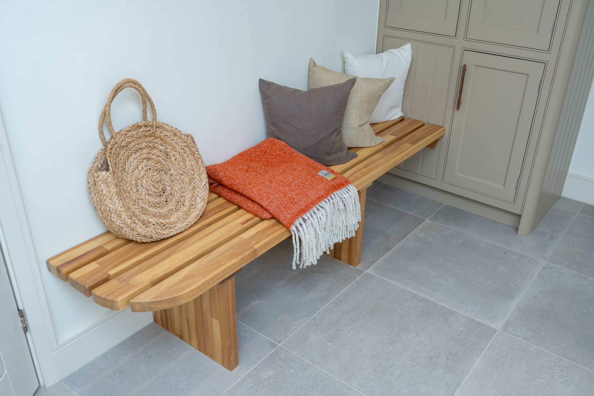 A wooden bench with pillows and a blanket on it in a hallway.