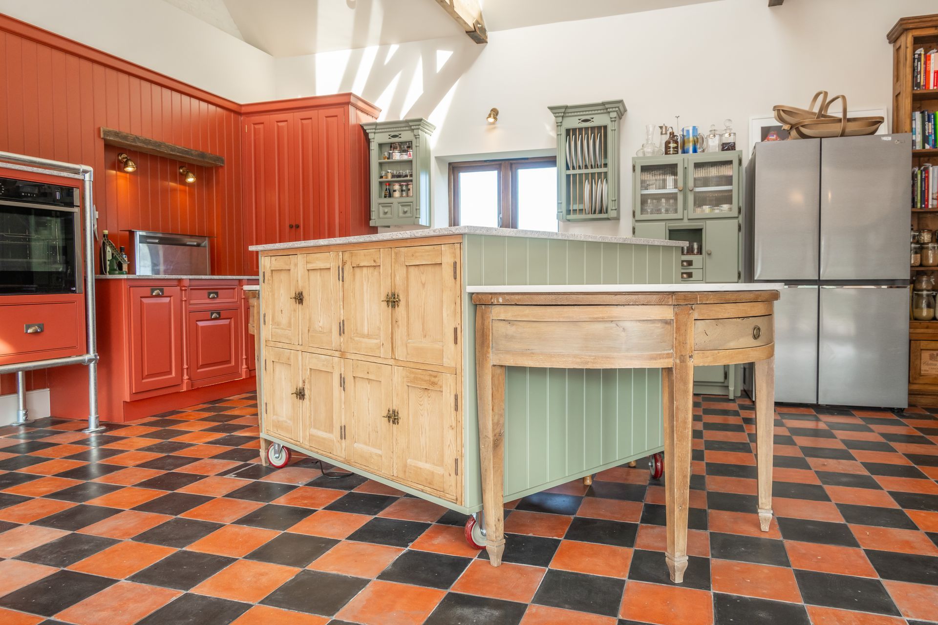 A kitchen with red cabinets and a checkered floor.