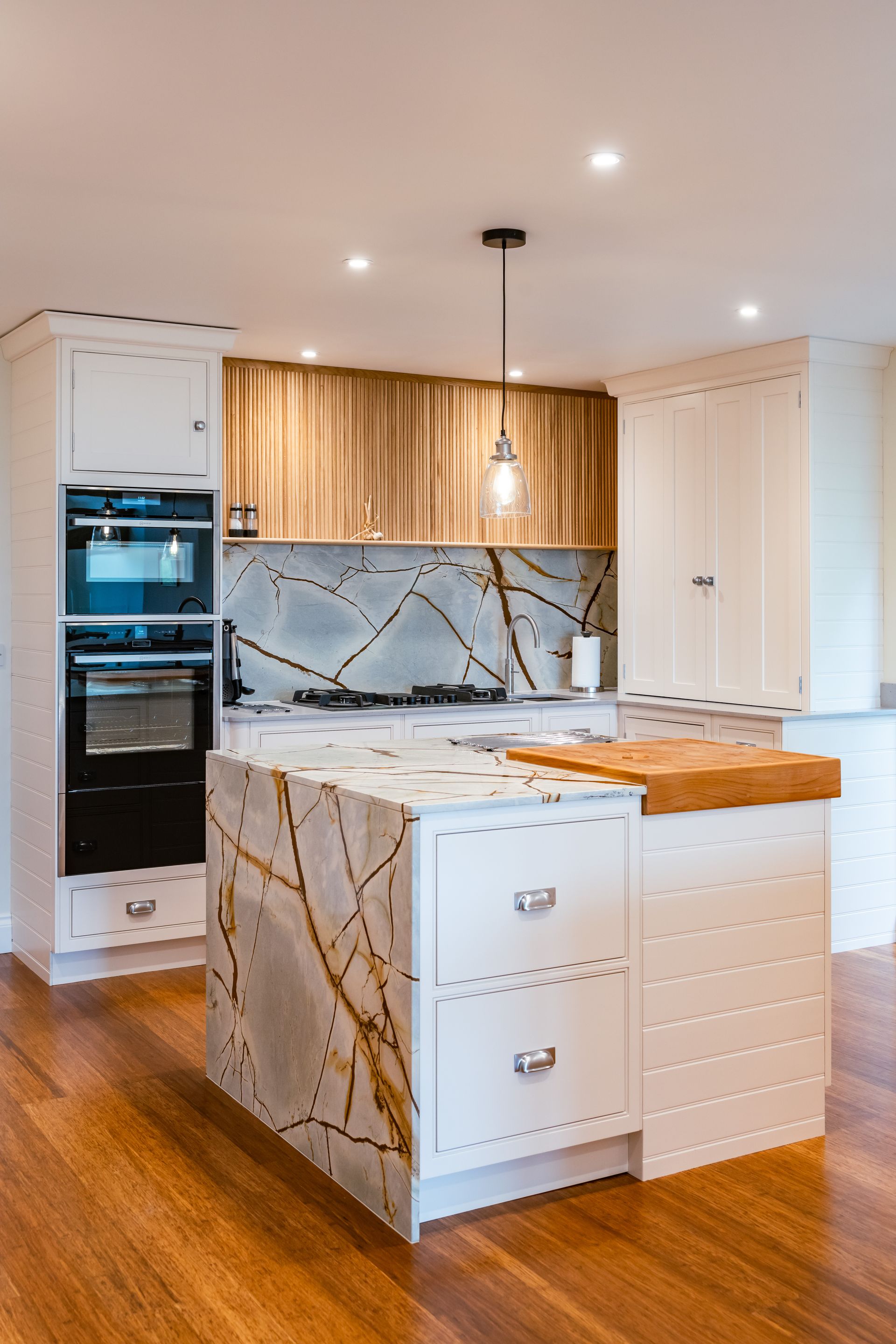 A kitchen with a large island in the middle and wooden floors.