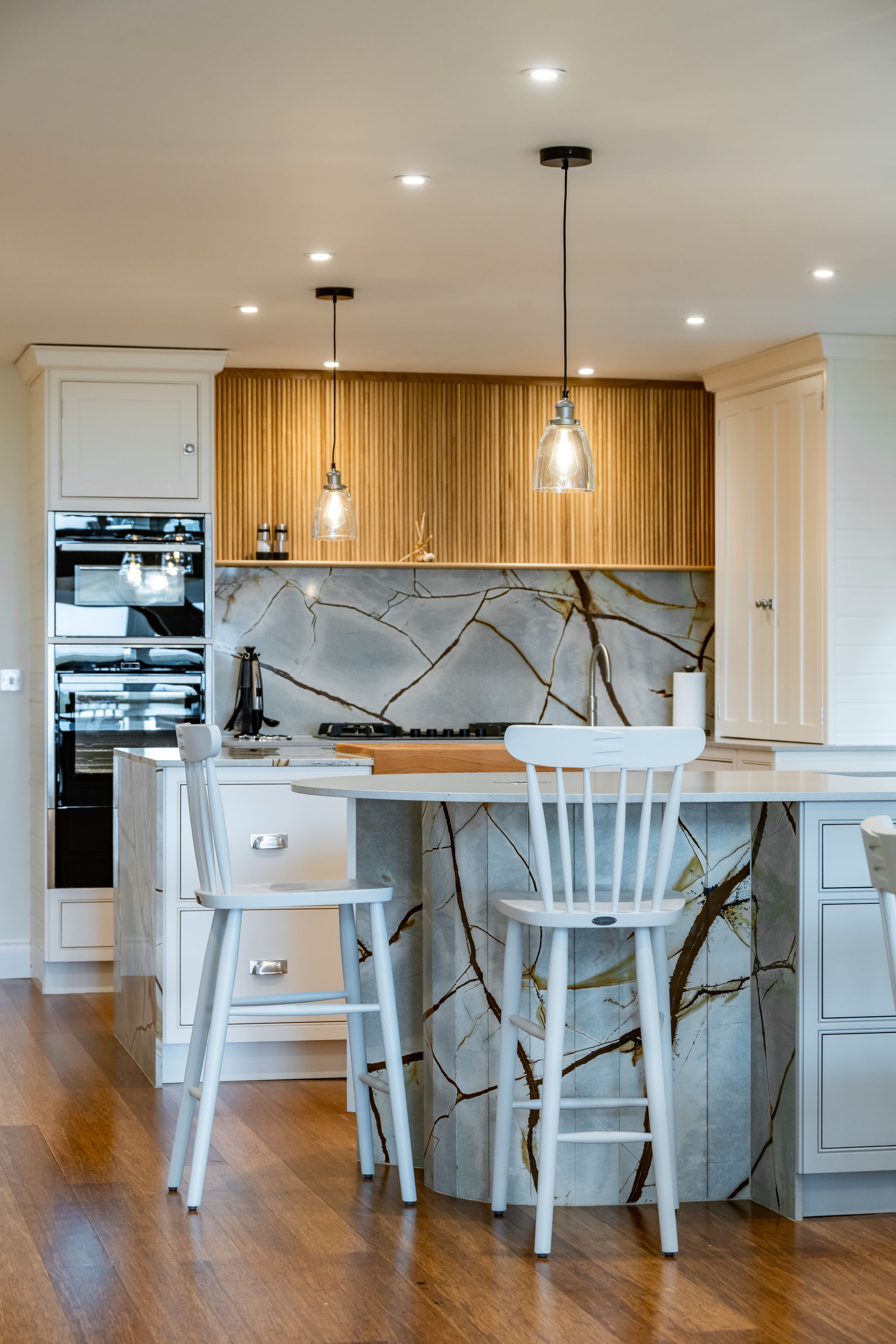 A kitchen with a marble counter top , white cabinets , and wooden cabinets.
